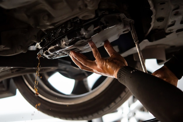 Der Automechaniker lässt die alte Automatikgetriebeflüssigkeit (ATF) oder das Getriebeöl in der Autowerkstatt ab, um das Öl in einem Getriebe des Automotors zu wechseln