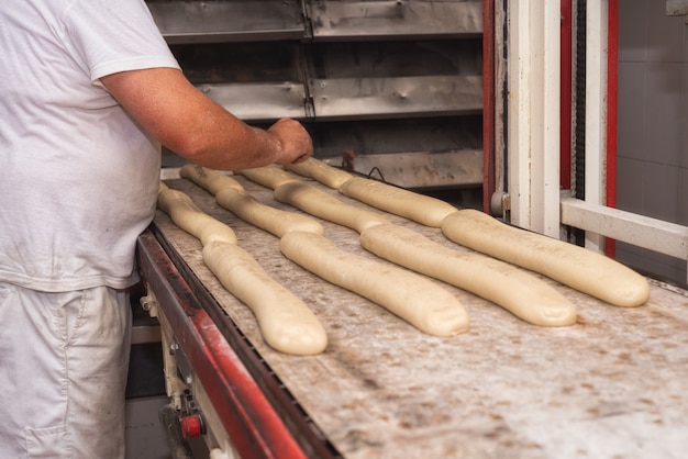 Der Bäcker, der ungekochte Brotteiglaibe vorbereitet, bereitet vor, um zu backen