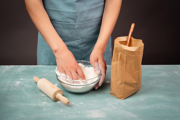 Der Bäcker knetet mit seinen Händen Teig für Brot oder Pizza und bereitet Zutaten für das Backen von Gebäck vor