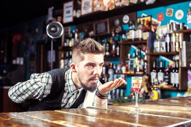 Foto der bärtige barkeeper beendet seine kreation intensiv im nachtclub