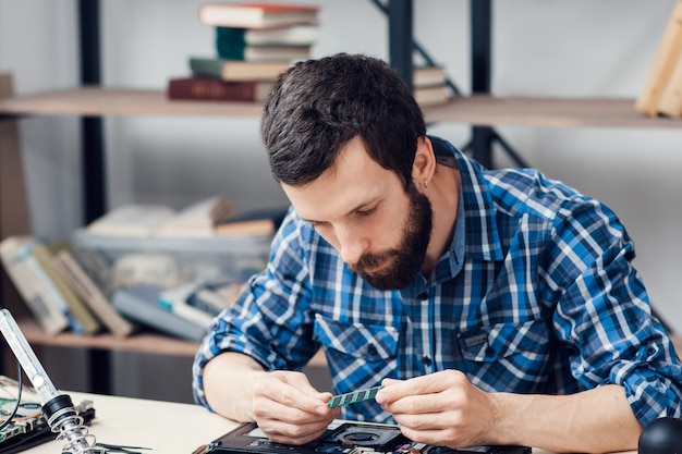 Der bärtige ingenieur untersucht die mikroschaltung