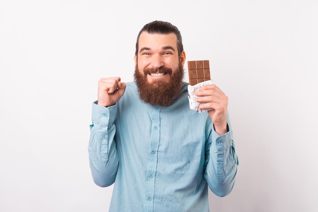 Der bärtige Mann freut sich über eine Schokoladenpause, während er eine hält.