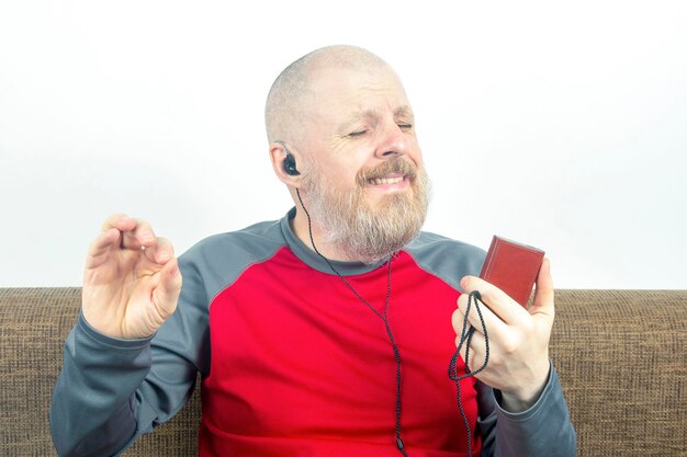 Der bärtige Mann hört gerne seine Lieblingsmusik über einen Audioplayer in kleinen Kopfhörern.