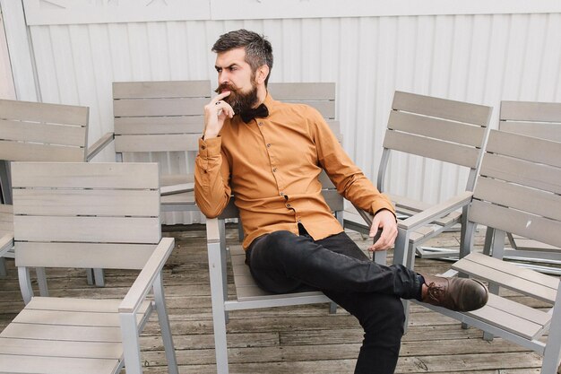 Der bärtige Mann sitzt allein auf einem Stuhl auf der Terrasse und denkt über das Leben nach