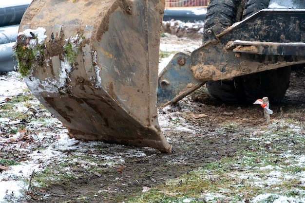 Der Bagger arbeitet auf der Baustelle, um die Pipeline im Winter auszutauschen Bohren von Löchern zum Verlegen neuer Rohre für die Zentralheizung in einem Wohngebiet