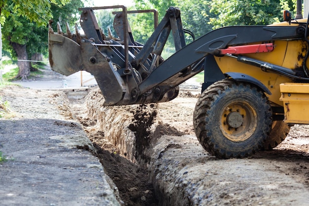 Der Bagger schläft einen Graben ein. Bauen in einem Vorort