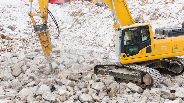 Der Bagger spaltet die Steine der Laufbahnausrüstung