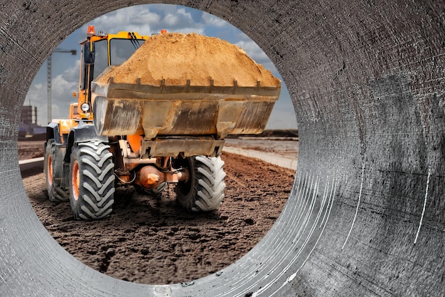 Der Baggerlader arbeitet mit einem Eimer zum Transport von Sand auf einer Baustelle Professionelle Baumaschinen für Erdarbeiten