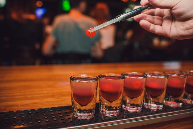 Der Barkeeper gießt Tequila vor dem Hintergrund der Bar in Glas.