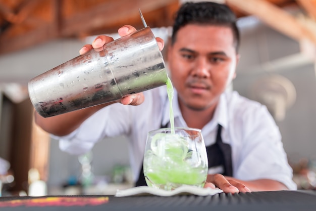 Der Barkeeper macht einen Cocktail an der Theke.