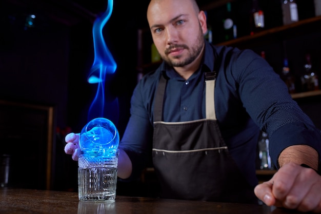 Der Barkeeper macht einen heißen alkoholischen Cocktail und zündet die Bar an