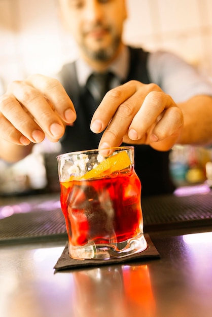 Der Barkeeper serviert ein rotes Getränk im Glas an der Theke