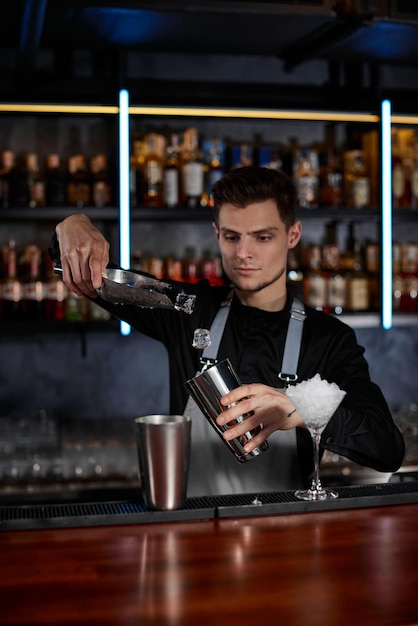 Der Barmann steckt die Eiswürfel in ein Glas