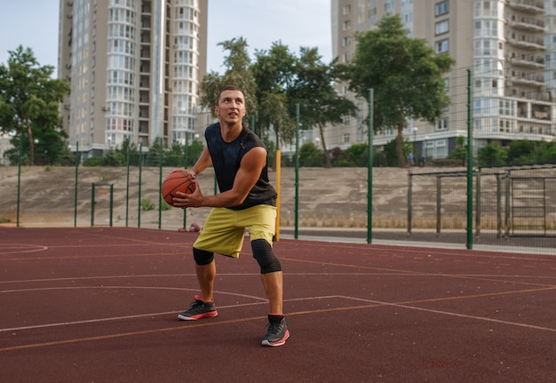 Der Basketballspieler bereitet sich auf ein Shooting auf dem Platz im Freien vor.