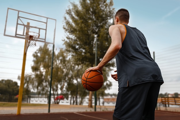 Der Basketballspieler bereitet sich auf einen Wurf auf dem Außenplatz vor.