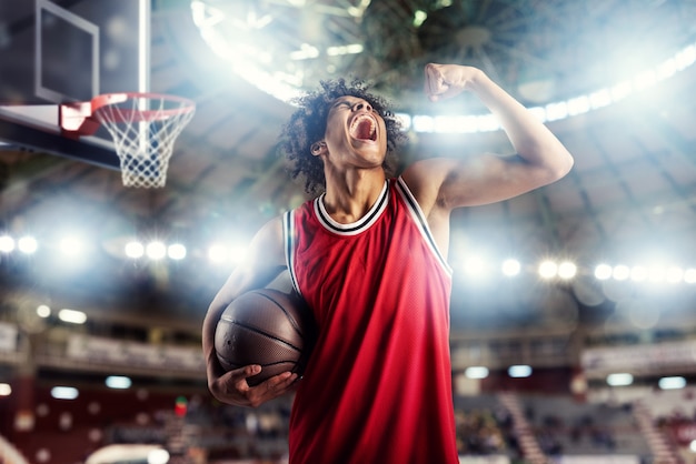 Der Basketballspieler gewinnt das Spiel im Korbstadion voller Zuschauer.