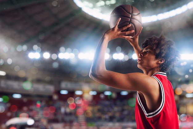 Der Basketballspieler wirft den Ball in den Korb im Stadion voller Zuschauer.