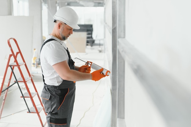 Der Baumeister füllt die Nähte an der Wand mit versiegeltem Silikon