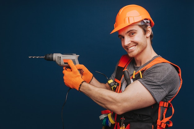 Der Baumeister hat Ausrüstung im Arm und lächelt