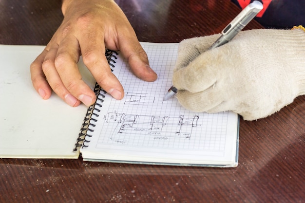 Der Baumeister macht eine Skizze des Hauses. Hand mit einem Stift zeichnet