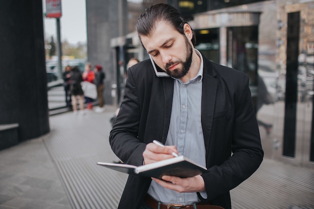 Der beschäftigte Mann hat es eilig, er hat keine Zeit, er wird unterwegs telefonieren. Geschäftsmann, der mehrere Aufgaben erledigt. Multitasking-Unternehmer.