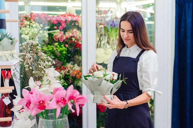 Der Besitzer eines Blumenladens macht einen Blumenstrauß mit weißen Rosen