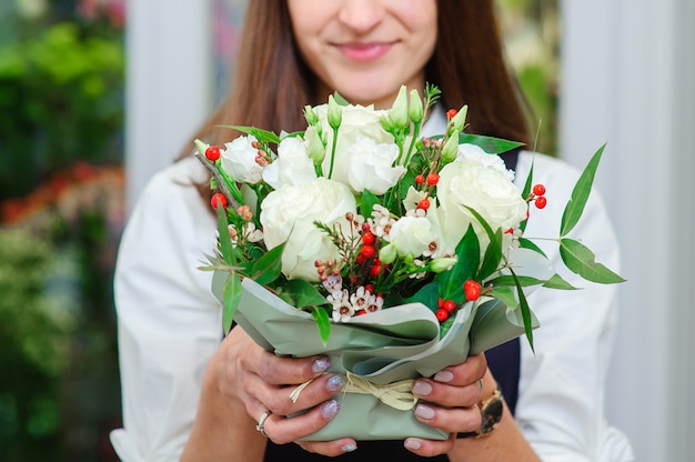 Der Besitzer eines Blumenladens macht einen Blumenstrauß mit weißen Rosen