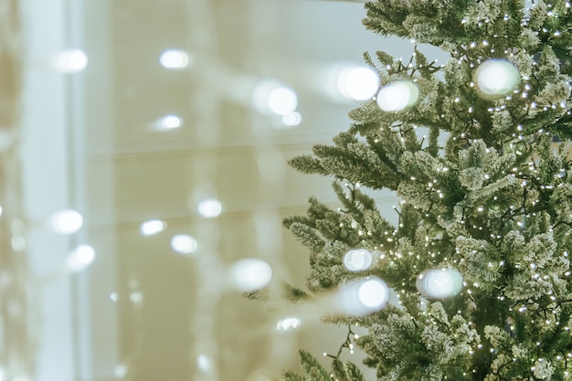 Der Blick aus dem Fenster mit Girlanden auf den Weihnachtsbaum. Schöner Weihnachtshintergrund mit Bokeh-Licht