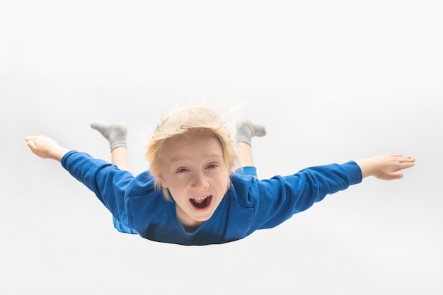 Der blonde Junge fällt von seinem Kopf. Flug ohne Fallschirm. Weißer Hintergrund.