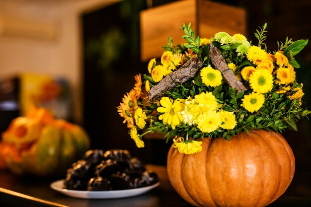 Der Blumenstrauß von Herbstblumen im Kürbis auf der Feier von Halloween