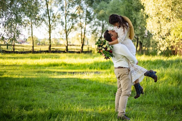 Der Bräutigam erhob sich und dreht die Braut Neuvermählte küssen sich auf dem Hintergrund der Natur im Innenhof des Hauses Nahaufnahme Erster Tanz der Hochzeit