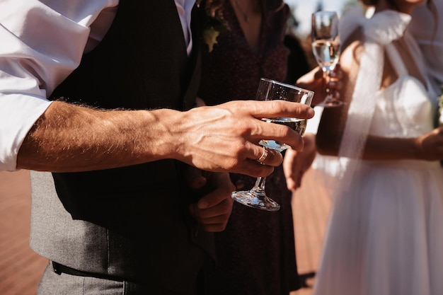 Der Bräutigam hält bei einer Hochzeitszeremonie ein Glas Champagner in der Hand