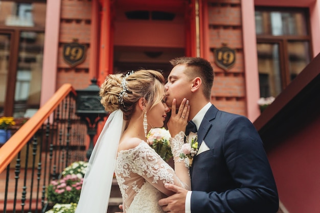 Der Bräutigam küsst zärtlich die Braut im Hintergrund ein wunderschönes altes Gebäude