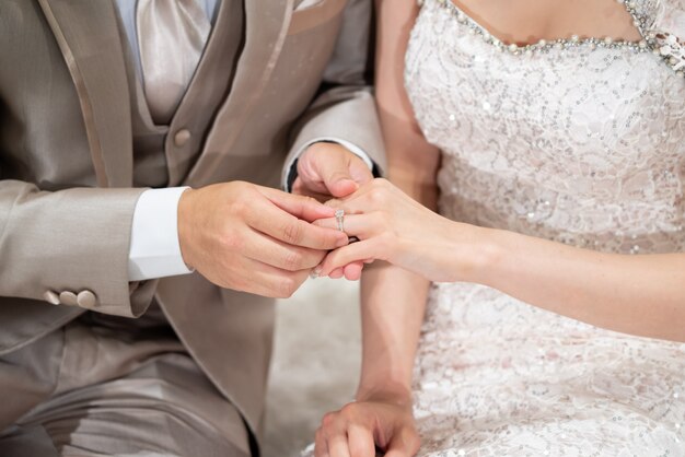 Der Bräutigam setzte einen Ehering in einen Brautfinger inThai Wedding Concept ein