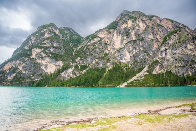 Der Braies-See, umgeben von Kiefernwäldern und den Felsketten der Dolomiten an bewölkten Tagen in Italien