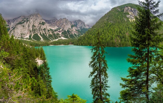 Der Braies-See, umgeben von Kiefernwäldern und den Felsketten der Dolomiten an bewölkten Tagen in Italien