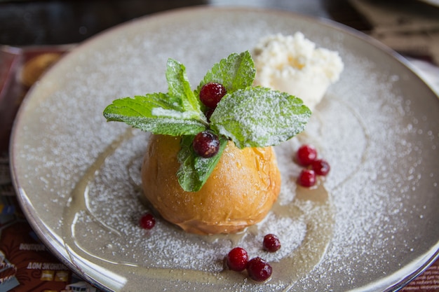 Der Bratapfel mit Eiscreme und Minze auf einer Keramikplatte. Nützlicher Nachtisch.