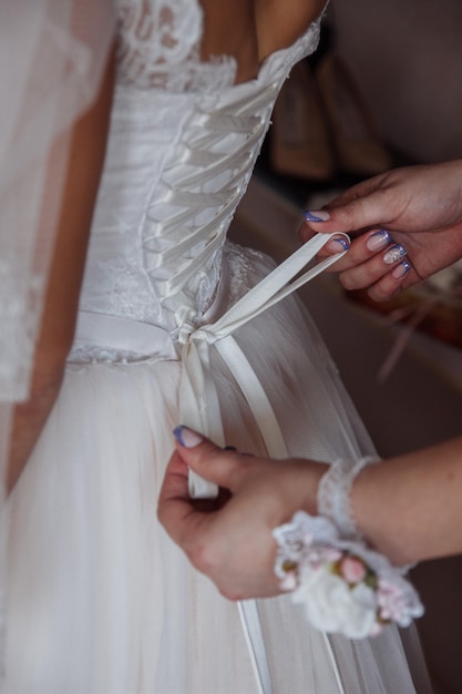 Der Braut wird geholfen, ein Kleid anzuziehen