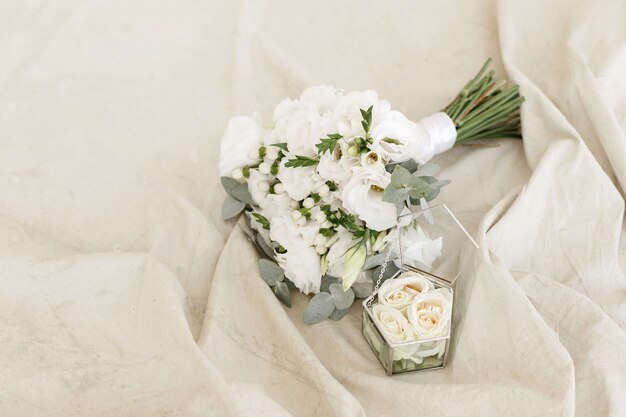 Der Brautstrauß aus weißen Blumen mit Eheringen in einer transparenten Box. Freier Platz für Text