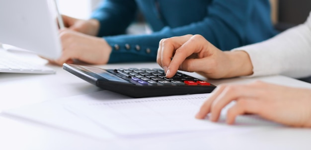 Der Buchhalter, der den Jahresabschluss überprüft oder mit dem Taschenrechnereinkommen für das Steuerformular zählt, übergibt Nahaufnahme