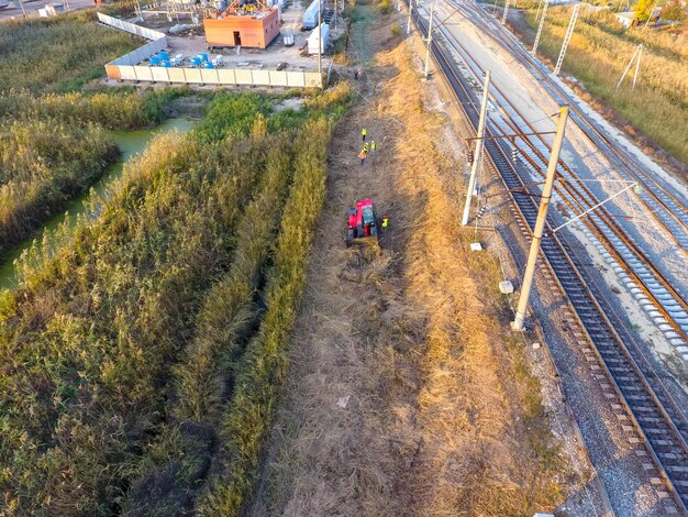 Foto der bulldozer räumt die fläche entlang der eisenbahnstrecken, das schilf mit dem bulldozer geräumt wird