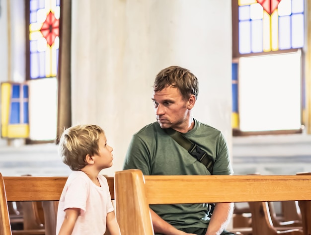 Der christliche Vater erzählt seinem Sohn biblische Geschichten über Jesus, der in der Kirche sitzt. Glaube, Religionsunterricht, moderne Kirche, Vatertag, väterliche Pflichten, Einfluss des Vaters auf die Bildung der Weltanschauung des Sohnes