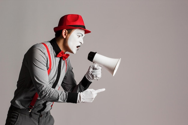 Der Clown MIM hält ein Megaphon Ausdruck von Emotionen auf grauem Hintergrund