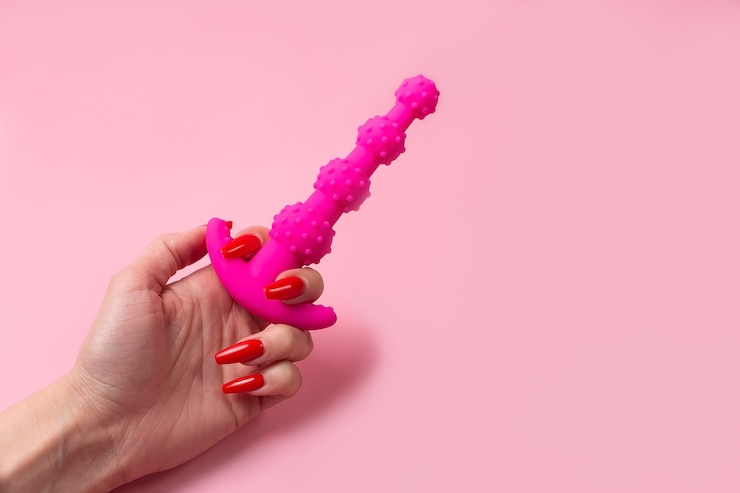 Foto der dildo in der hand auf einem rosa hintergrund, sexspielzeug