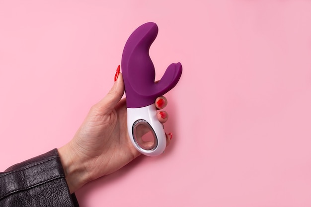 Der Dildo in der Hand auf einem rosa Hintergrund, Sexspielzeug