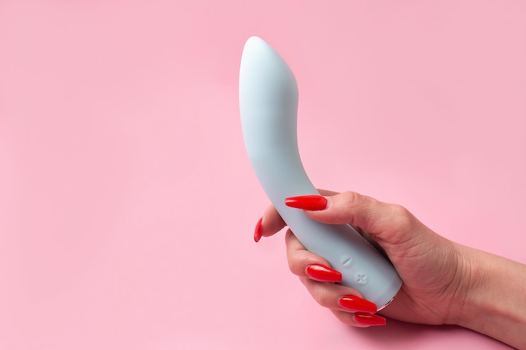 Foto der dildo in der hand auf einer rosa wand, sexspielzeug