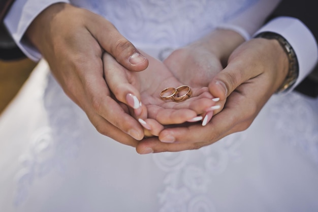 Der Ehemann umarmt sanft die Hände der Braut mit Eheringen