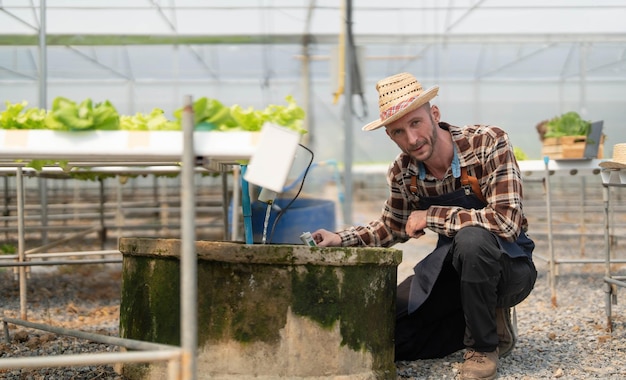 Der Eigentümer des Hydroponik-Gemüsegartens überprüft die Qualität des Gemüses und überprüft oder zeichnet das Wachstum des Gemüses im Garten Gemüse im Gewächshaus auf