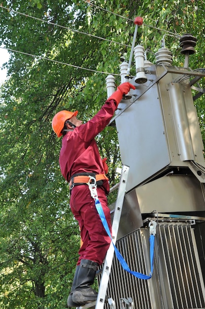 Der Elektriker installiert die Erdung an der Stromleitung, bevor er das Umspannwerk repariert