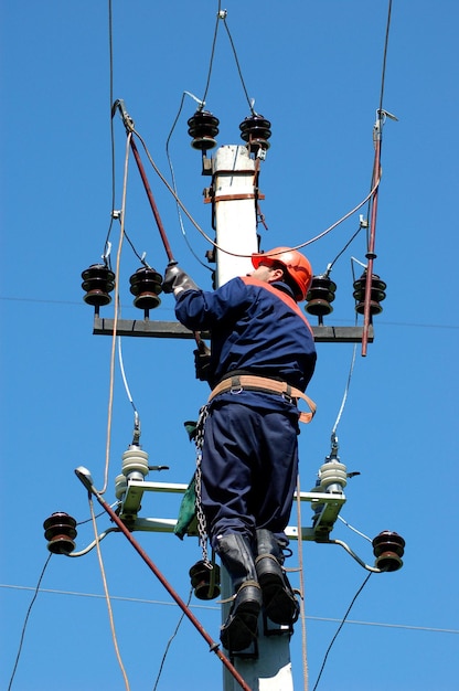 Der Elektriker installiert die Erdung an einer Stromleitung, bevor er sie repariert.